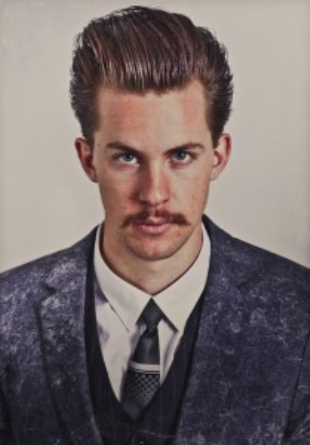 Pompadour com undercut e mechas ultra-longas no topo, combinado com bigode.