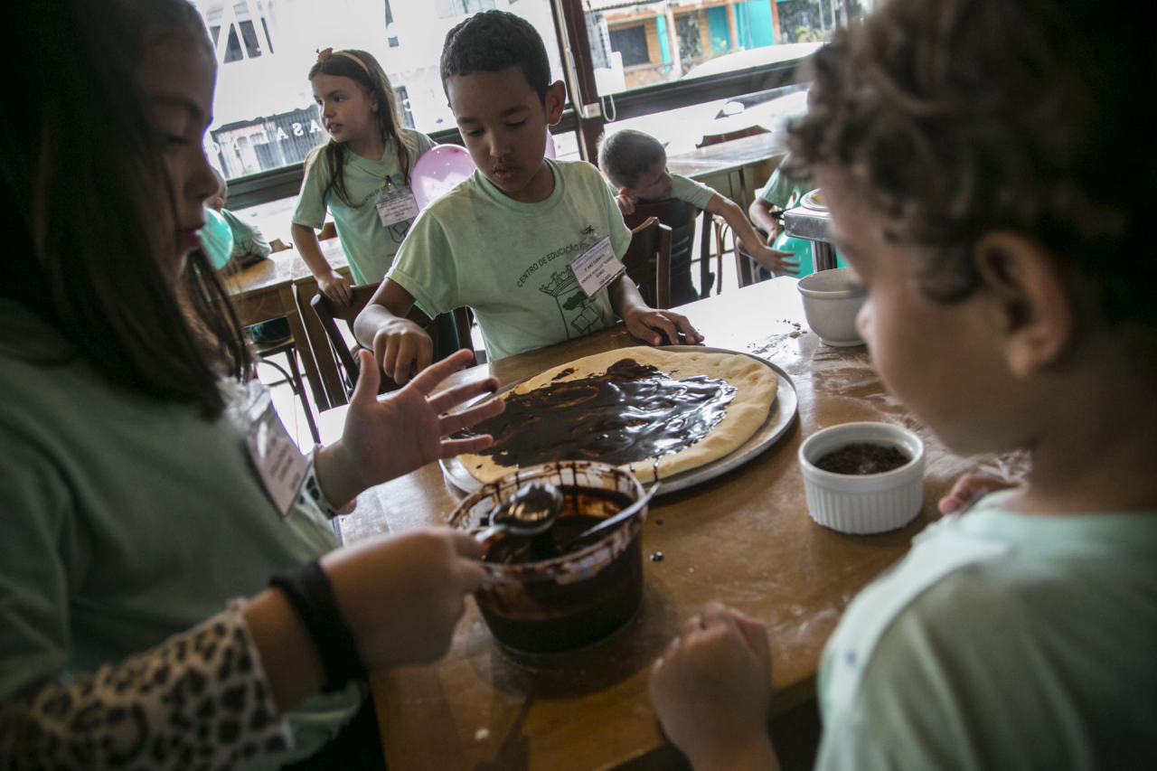 Andrew, ao centro, não pensou duas vezes depois que o chef lhe disse que poderia lamber a colher cheia de chocolate. Foto: Marcelo Andrade/Gazeta do Povo